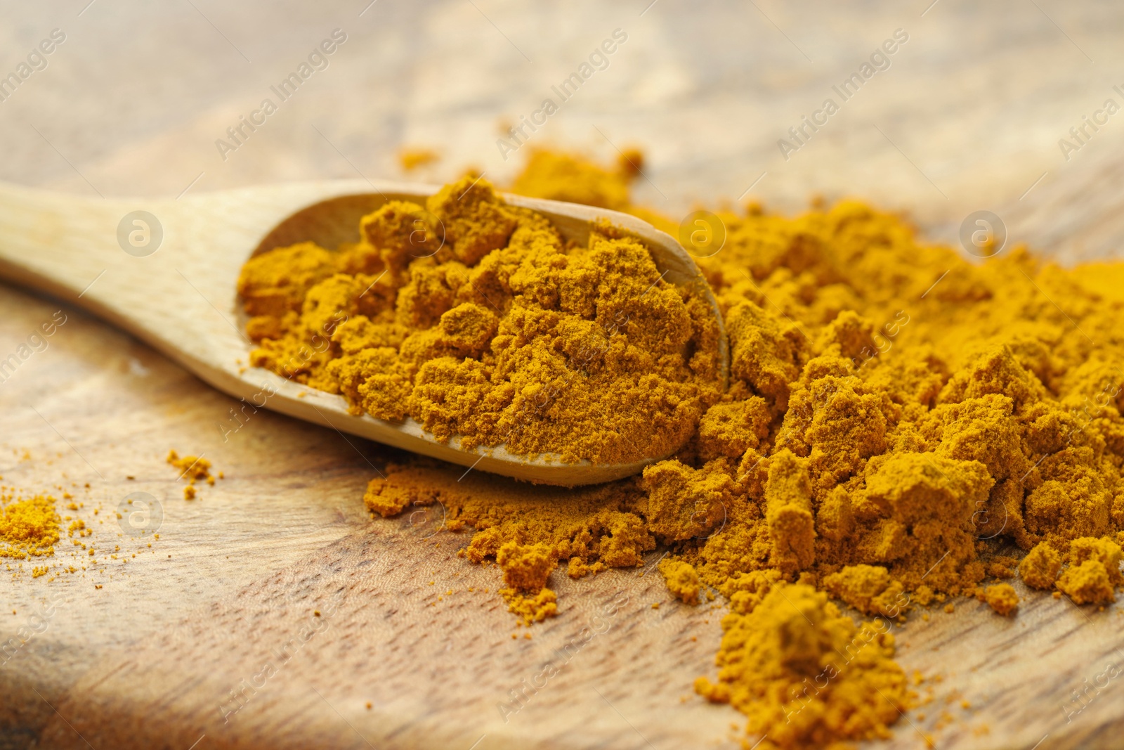 Photo of Turmeric powder and spoon on table, closeup