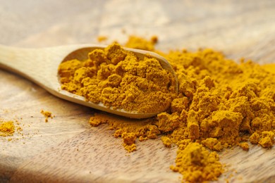 Photo of Turmeric powder and spoon on table, closeup