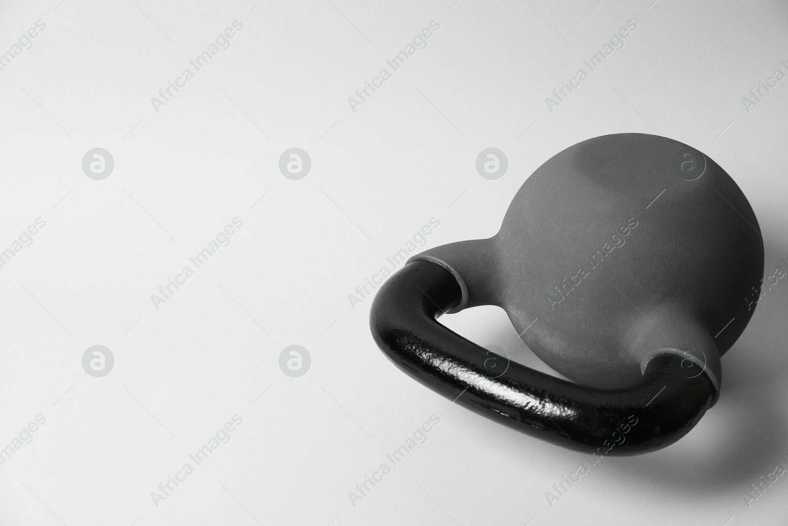 Photo of One metal kettlebell on grey background, space for text. Sports equipment