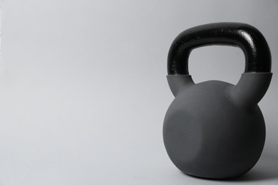 Photo of One metal kettlebell on grey background, space for text. Sports equipment