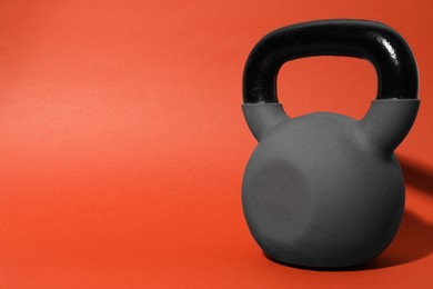 Photo of One metal kettlebell on coral background, space for text. Sports equipment