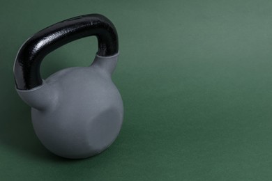 Photo of One kettlebell on dark green background. Space for text