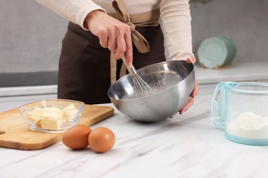 Photo of Woman making dough at white marble table indoors, closeup