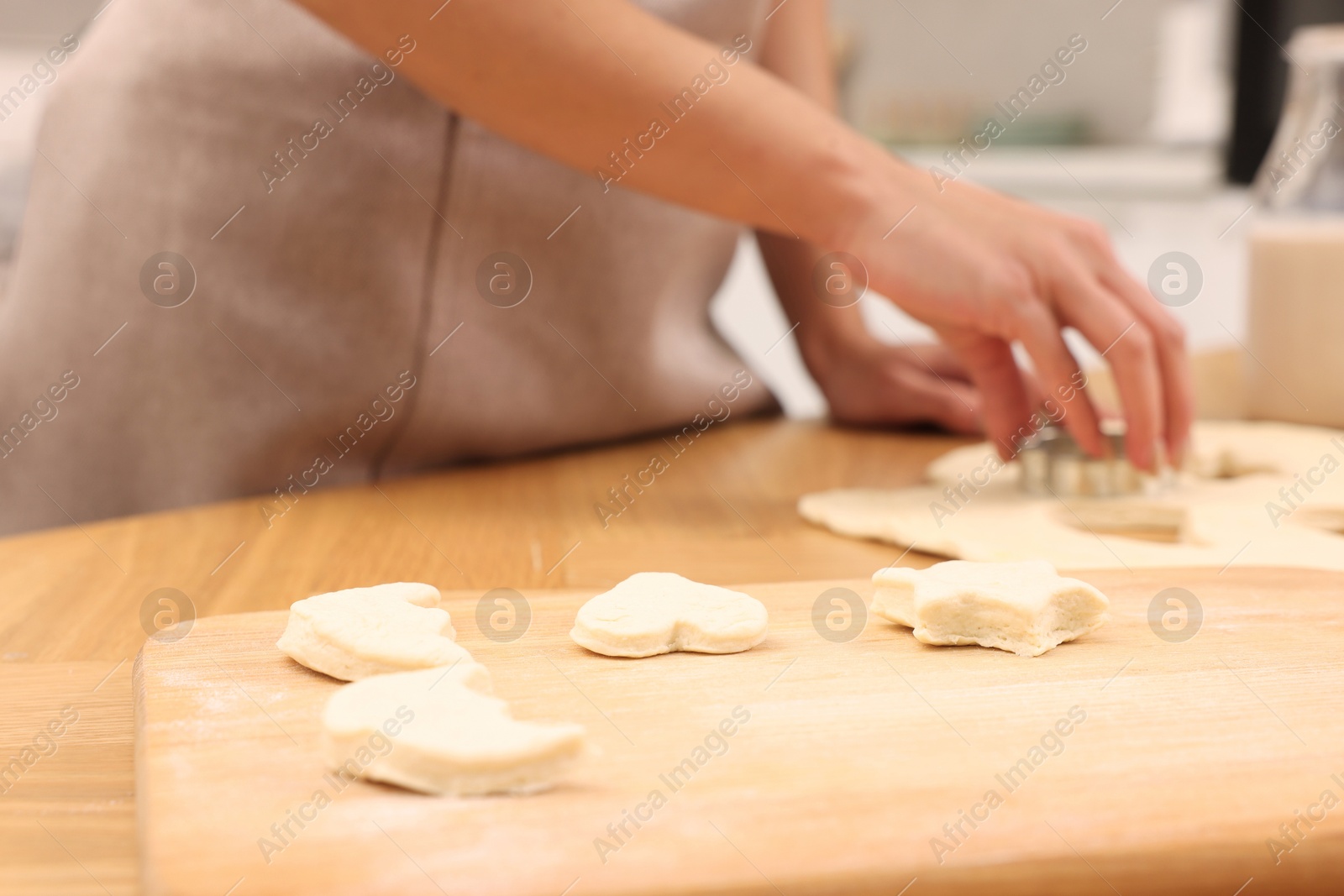 Photo of Woman cutting out cookies at wooden table indoors, closeup