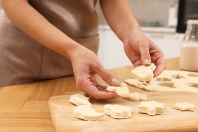 Photo of Woman with raw cookies at wooden table, closeup