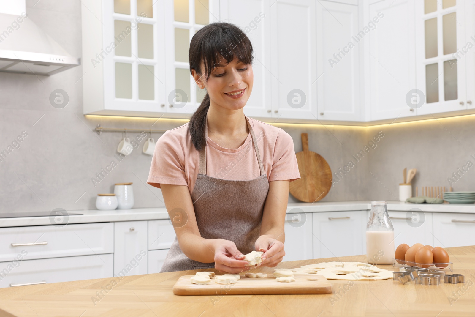 Photo of Woman with raw cookies at wooden table