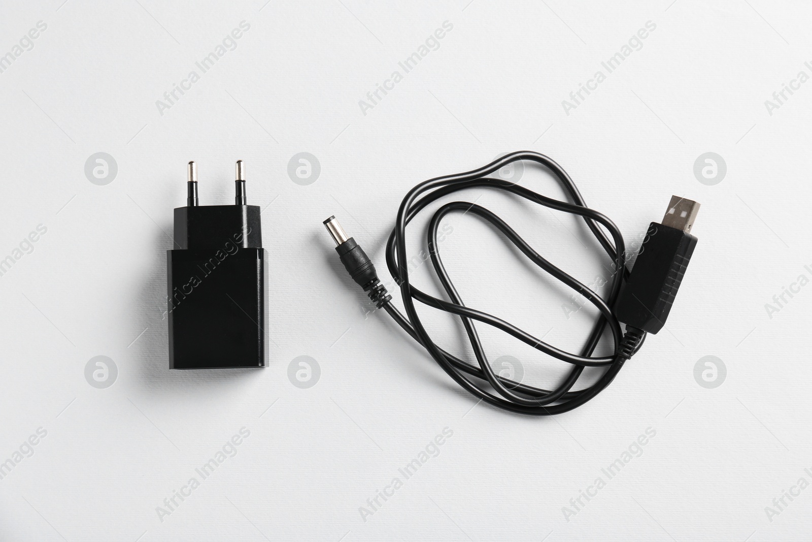 Photo of USB power adapter and charge cable on white background, flat lay