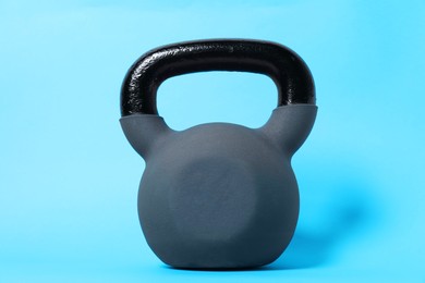 Photo of One kettlebell on light blue background. Sport equipment