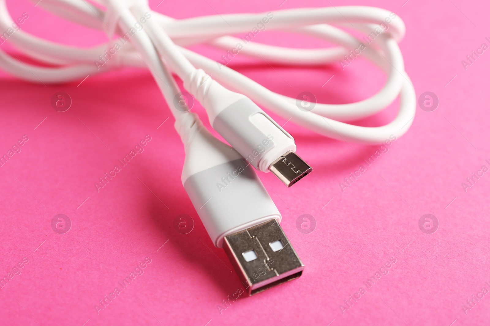 Photo of USB charge cable on pink background, closeup