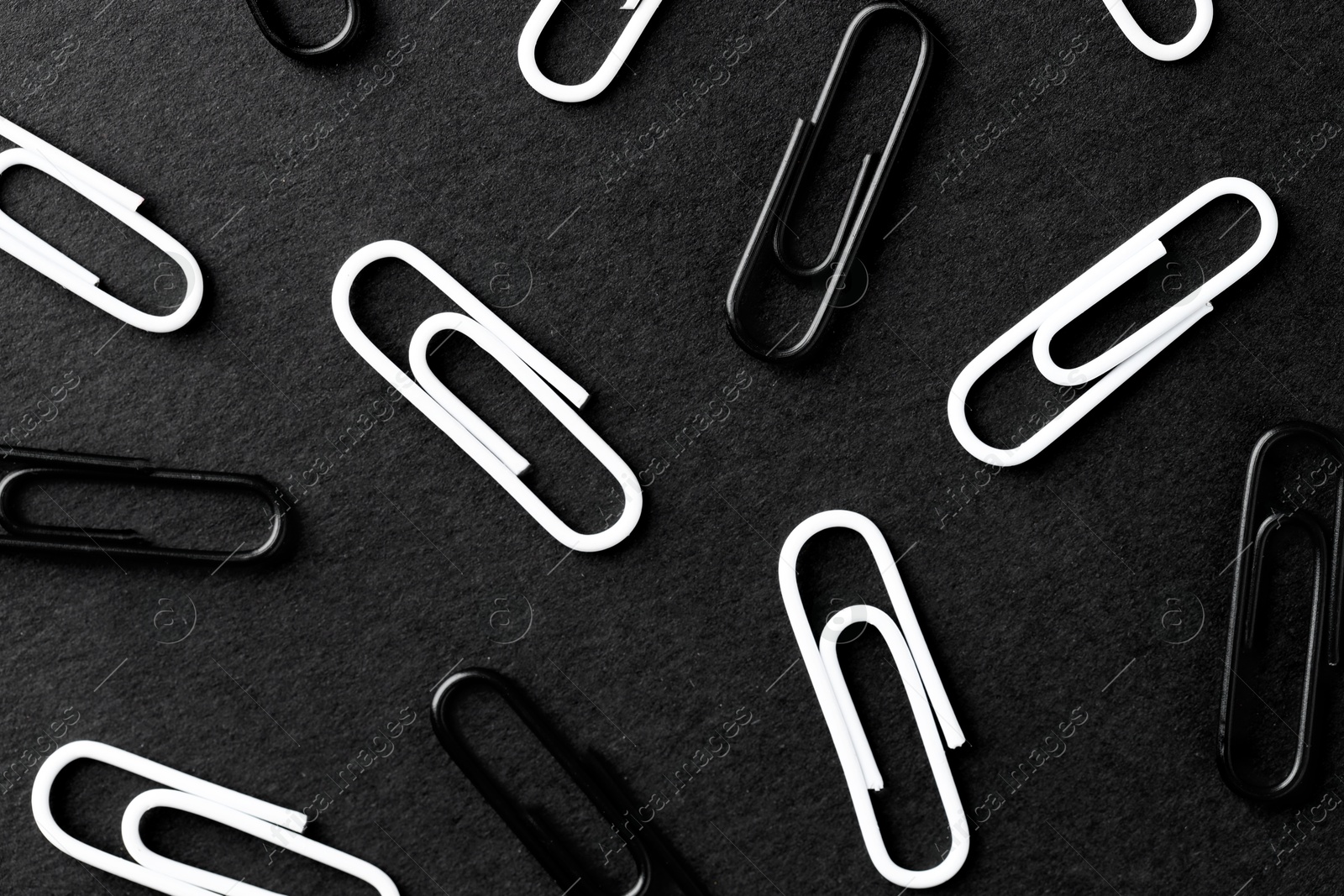 Photo of Many paper clips on black background, flat lay