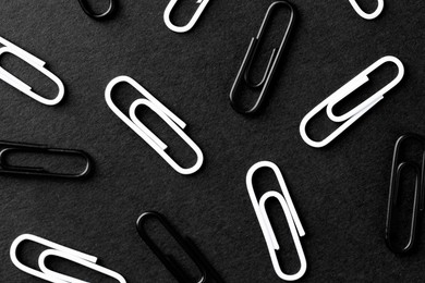 Many paper clips on black background, flat lay