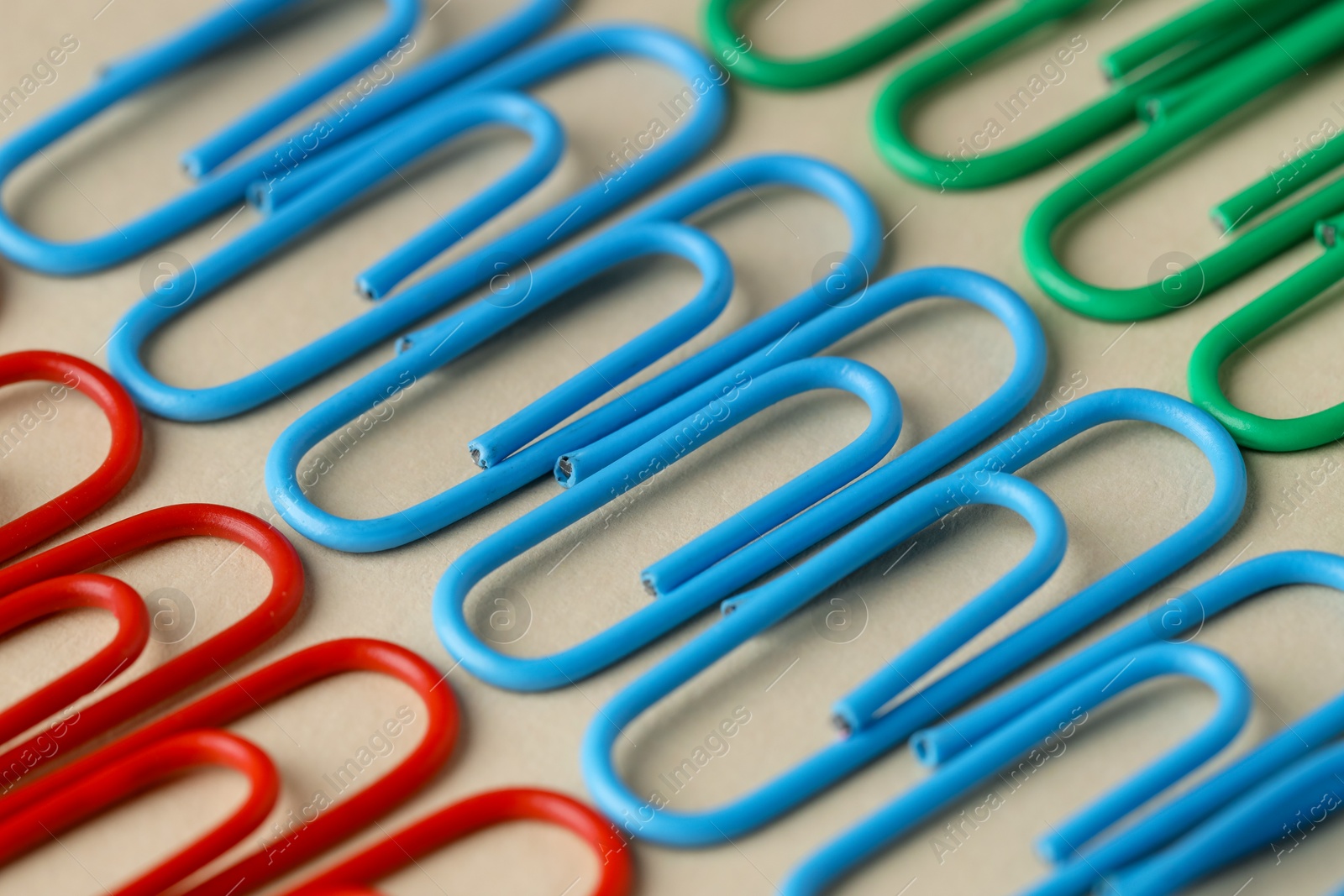 Photo of Colorful paper clips on beige background, closeup