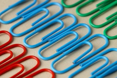 Colorful paper clips on beige background, closeup