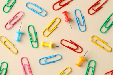 Photo of Paper clips and pins on beige background, flat lay