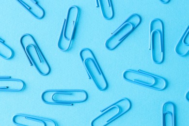 Photo of Many paper clips on light blue background, flat lay