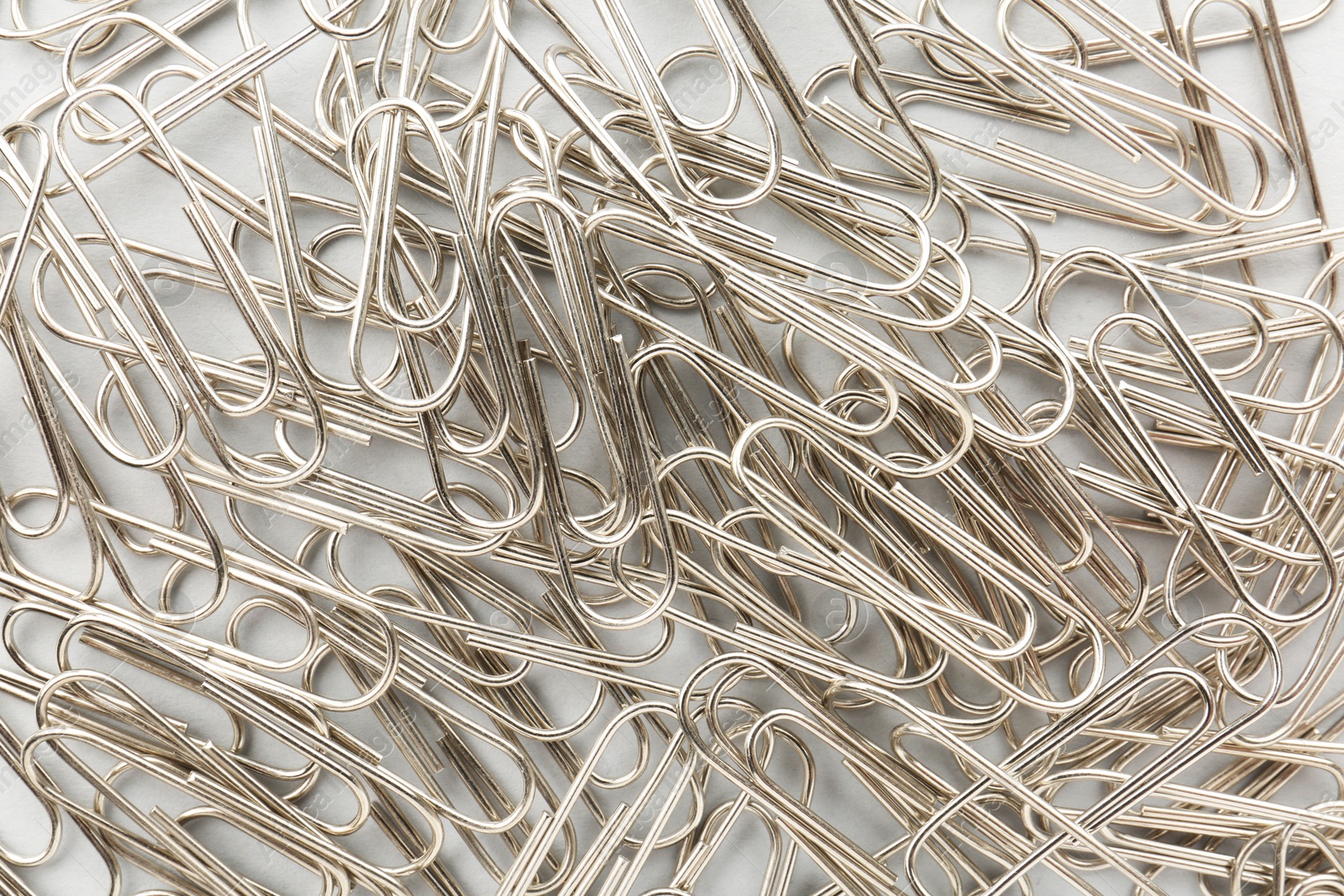 Photo of Metal paper clips on light background, top view