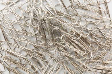 Metal paper clips on light background, top view