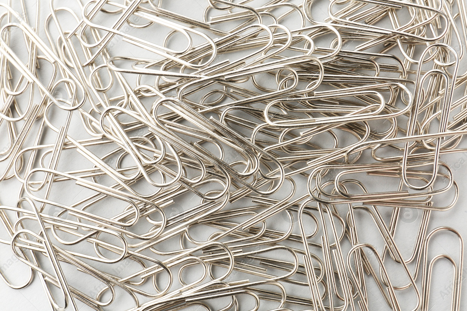 Photo of Metal paper clips on light background, top view