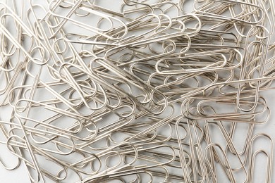 Metal paper clips on light background, top view