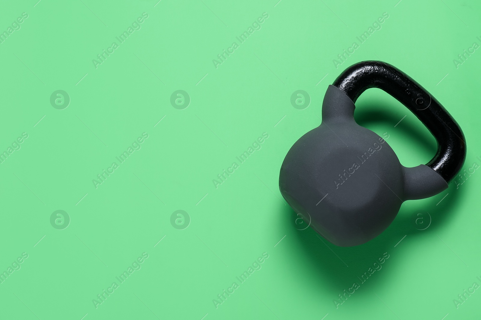 Photo of One kettlebell on green background, top view. Space for text