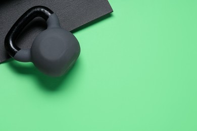 Photo of Kettlebell and mat on green background, top view. Space for text