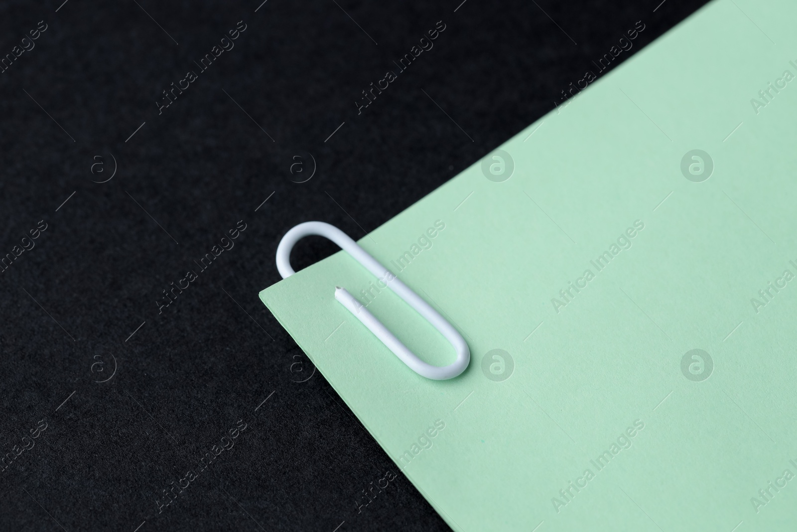 Photo of Paper note with clip on black table, closeup. Space for text