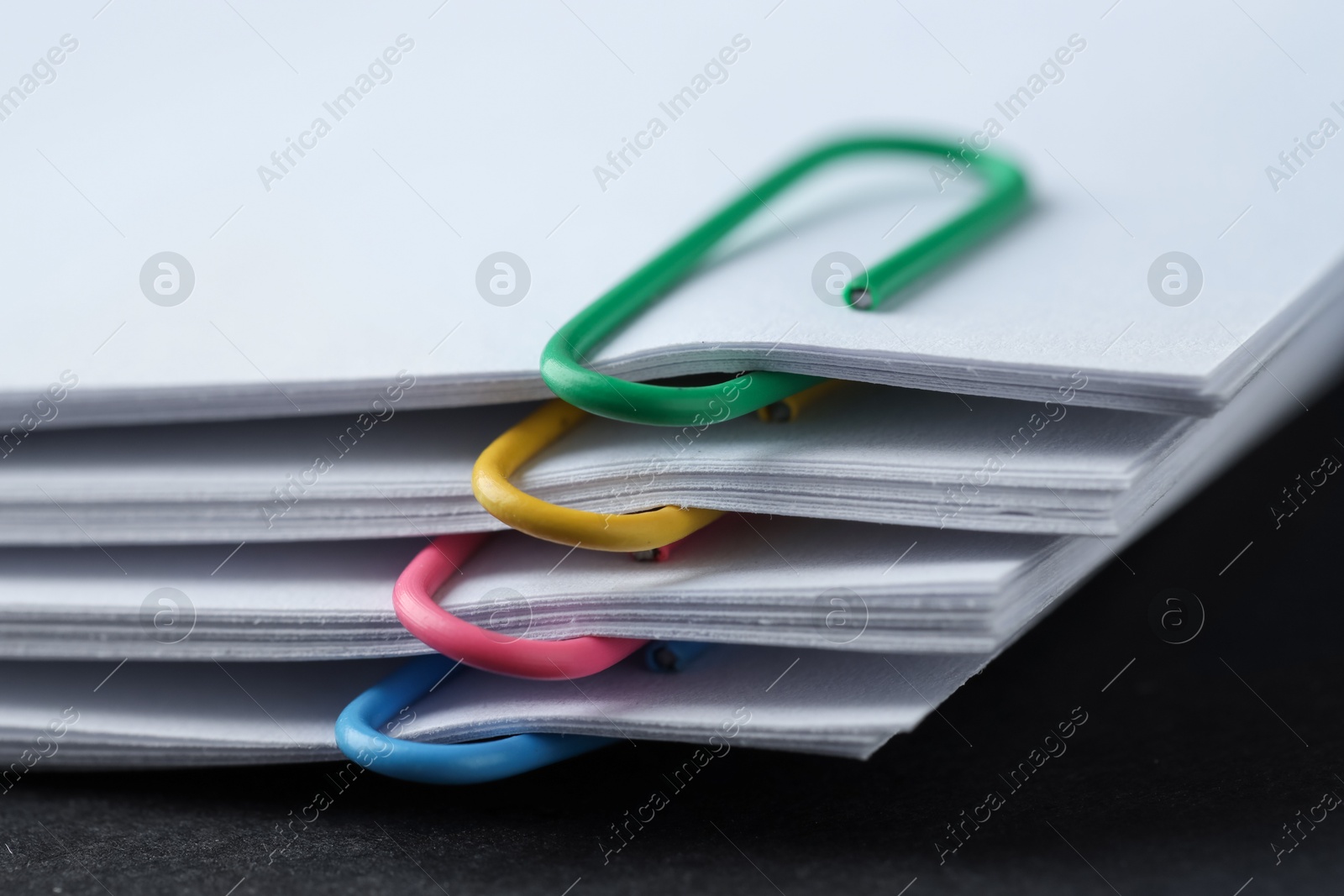 Photo of Paper notes with clips on black table, closeup