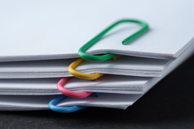 Paper notes with clips on black table, closeup