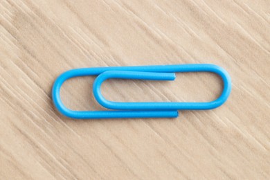 One blue paper clip on wooden table, top view