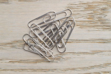 Many metal paper clips on wooden table, top view