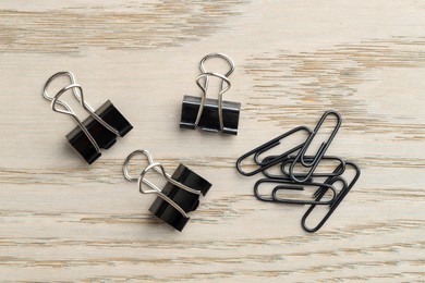 Photo of Many black paper clips on wooden table, flat lay