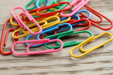 Photo of Many colorful paper clips on wooden table, closeup