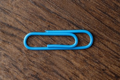 One blue paper clip on wooden table, top view