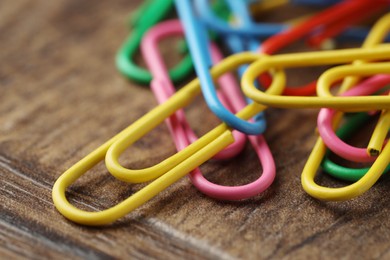 Photo of Many colorful paper clips on wooden table, closeup