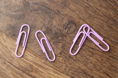 Photo of Many violet paper clips on wooden table, flat lay