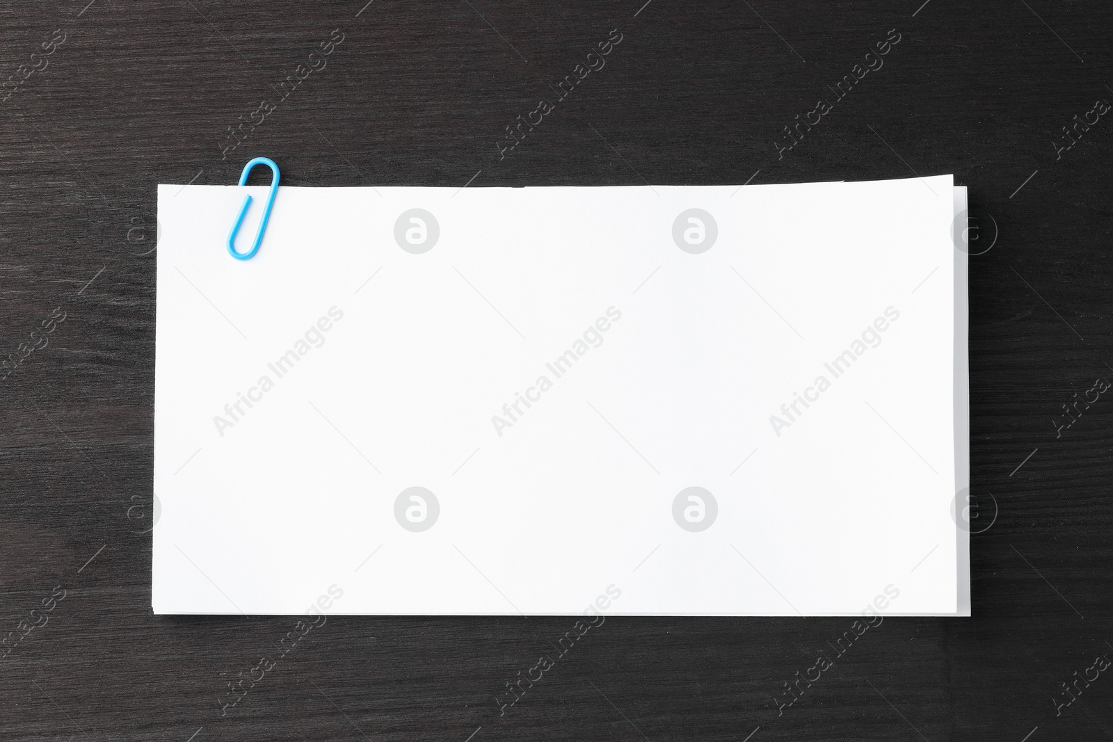 Photo of Paper notes with clip on black wooden table, top view. Space for text