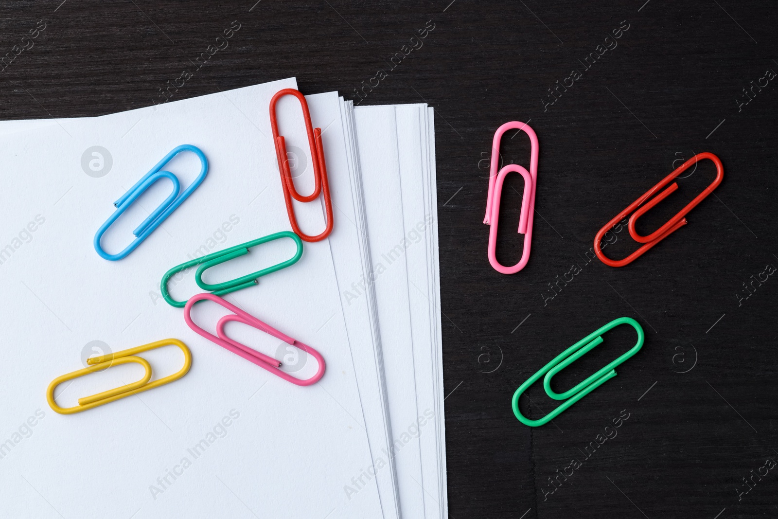 Photo of Many colorful clips and paper notes on black wooden table, flat lay