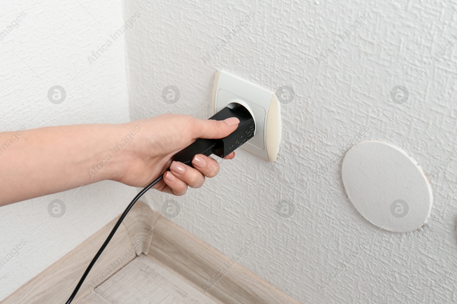 Photo of Woman plugging USB power adapter with charge cable into electrical socket indoors, closeup