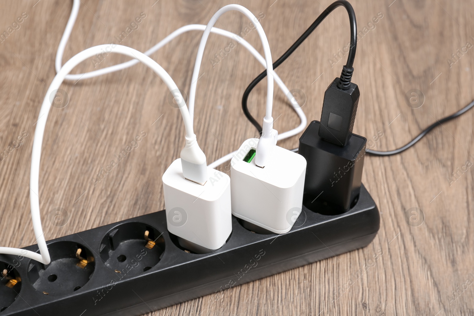 Photo of USB adapters with charge cables in power strip on floor, closeup