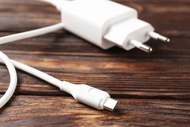 Photo of USB power adapter with charge cable on wooden table, closeup