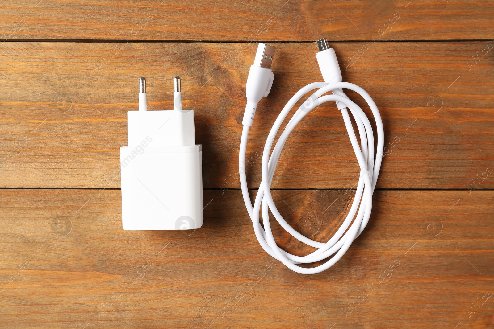 Photo of USB power adapter with charge cable on wooden table, top view