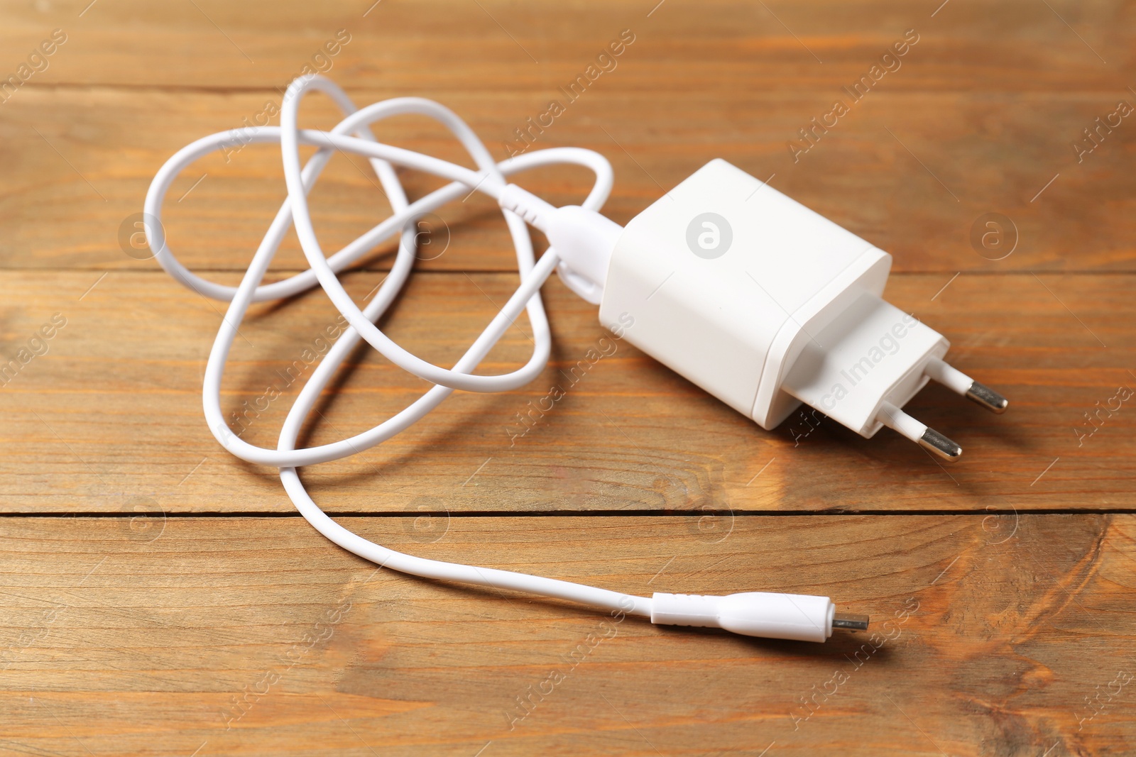 Photo of USB power adapter with charge cable on wooden table, closeup