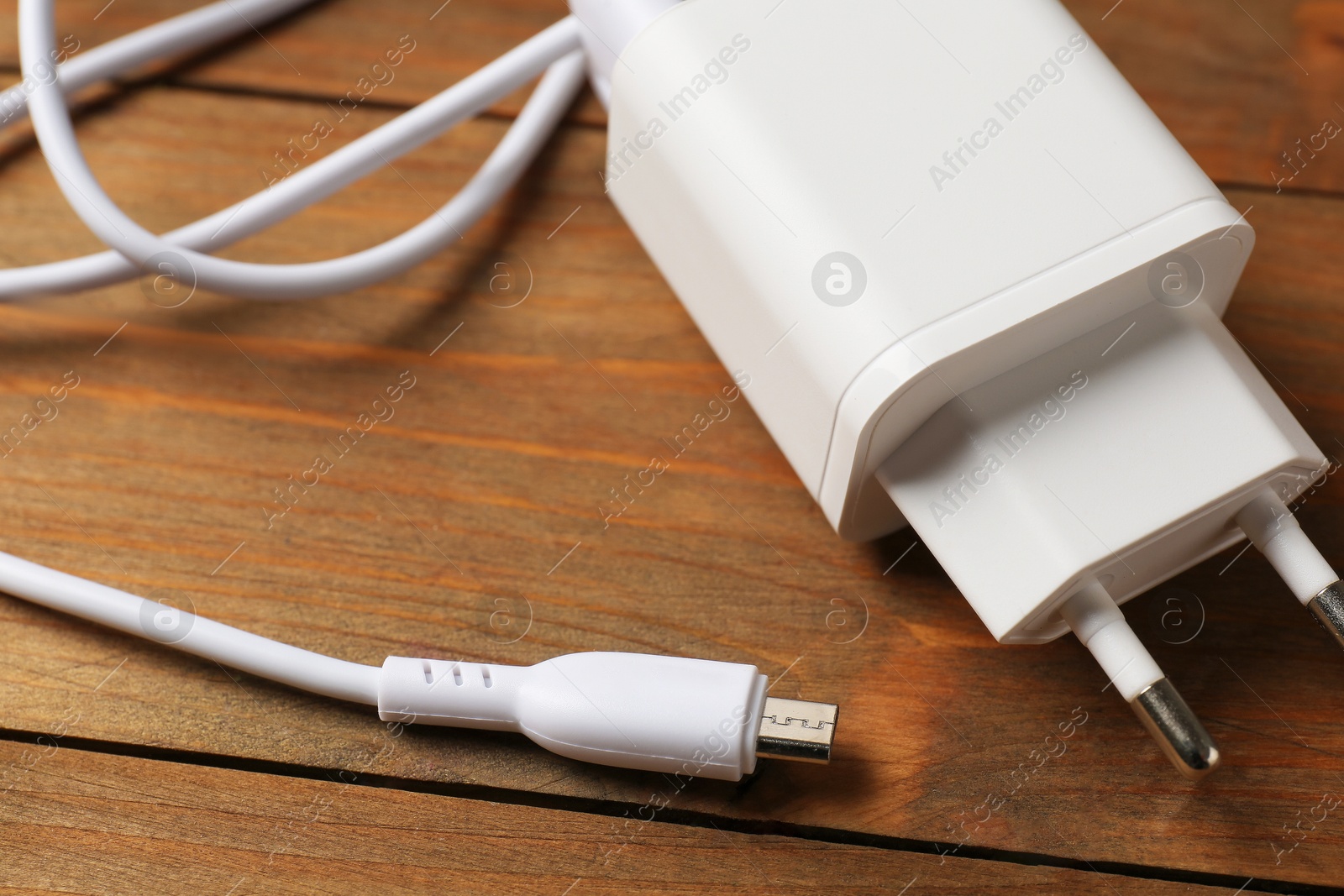 Photo of USB power adapter with charge cable on wooden table, closeup