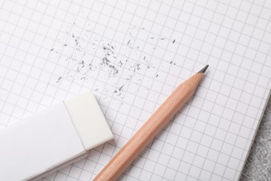 Photo of Eraser, pencil, scraps and notebook on table, top view