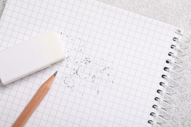 Photo of Eraser, pencil, scraps and notebook on table, top view