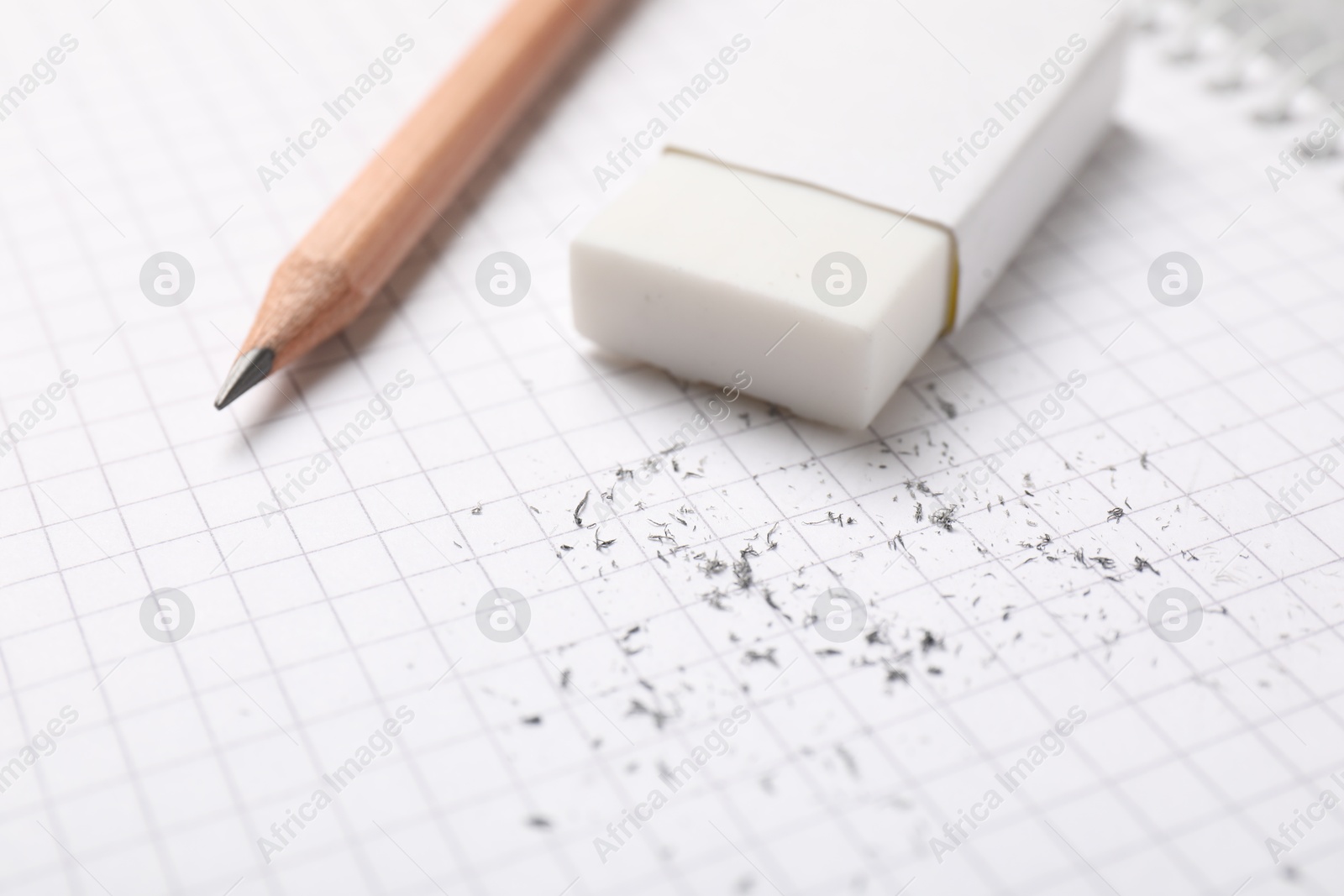 Photo of Eraser, pencil and scraps on notebook, closeup