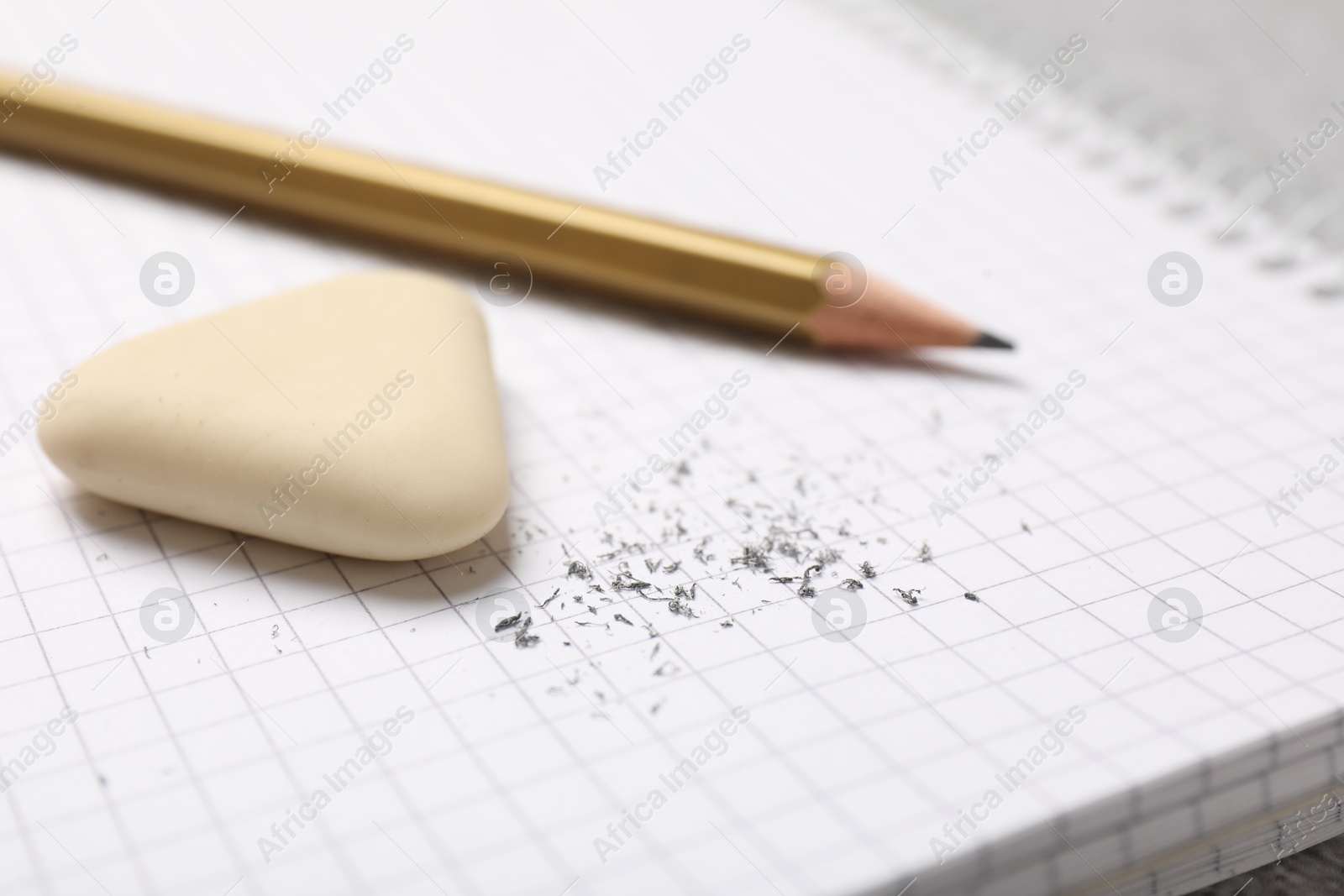 Photo of Eraser, pencil and scraps on notebook, closeup