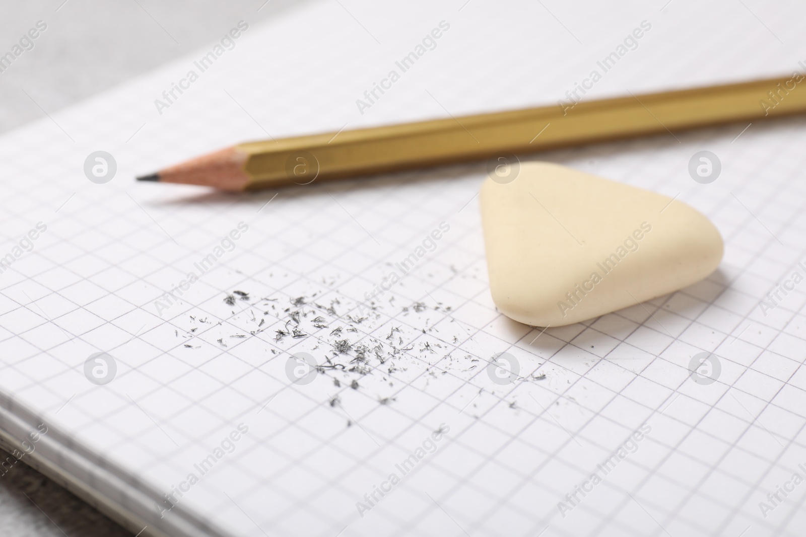 Photo of Eraser, pencil and scraps on notebook, closeup