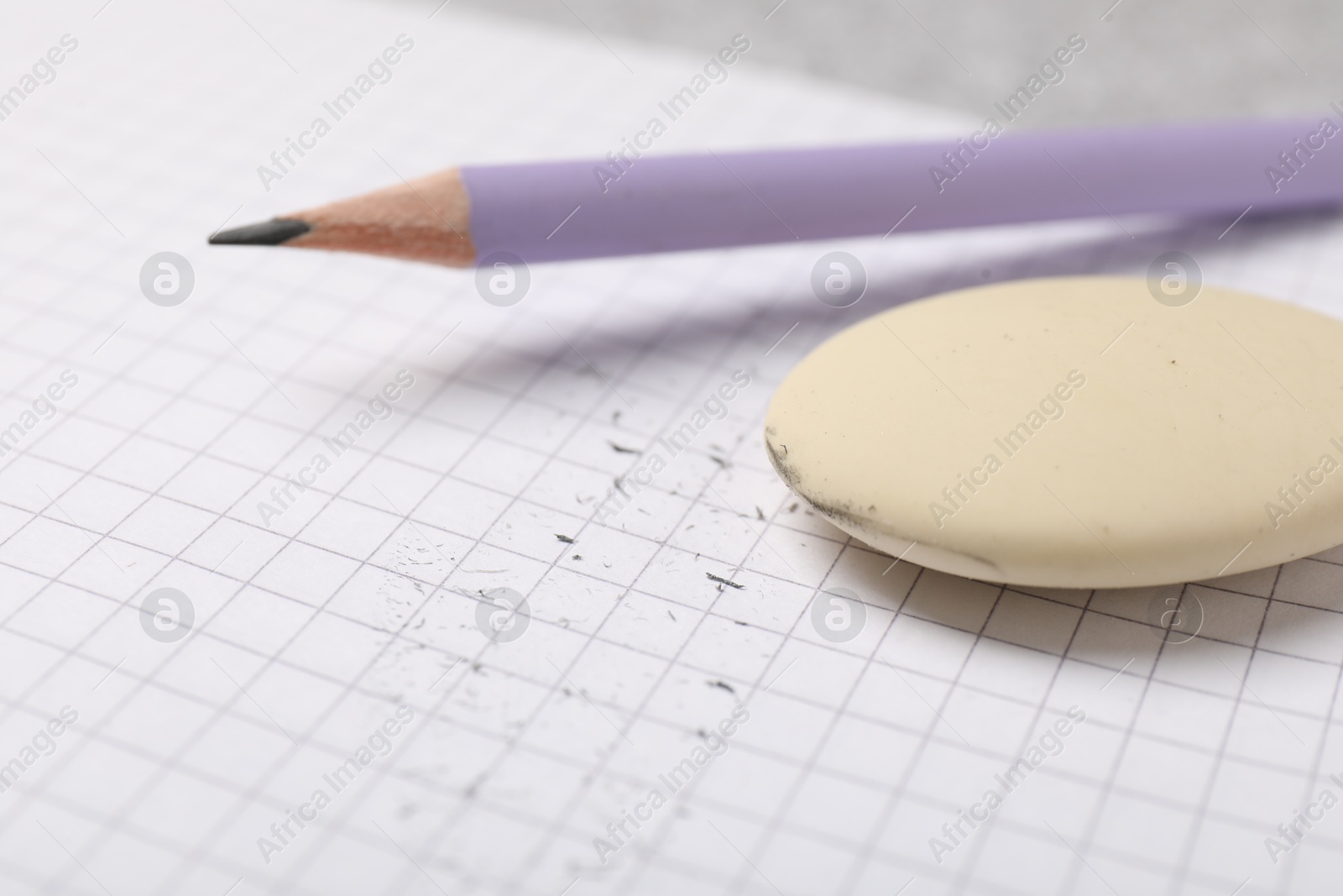 Photo of Eraser, pencil, scraps and notebook on table, closeup