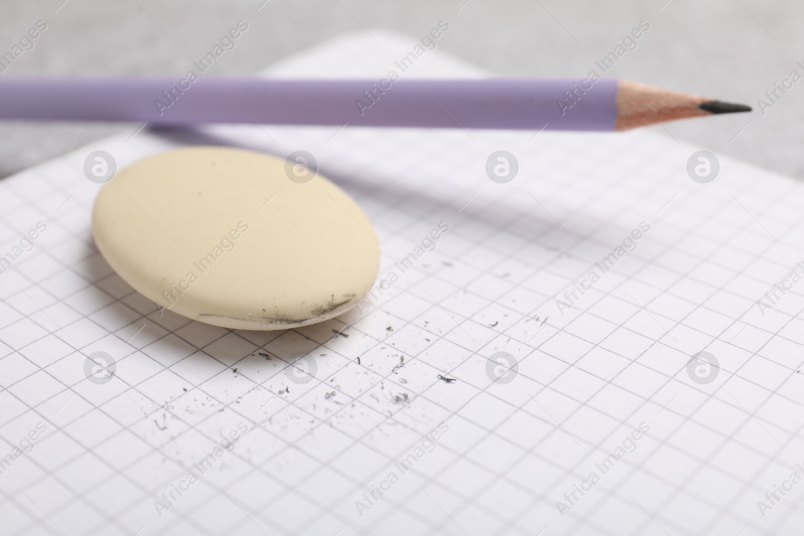 Photo of Eraser, pencil, scraps and notebook on table, closeup